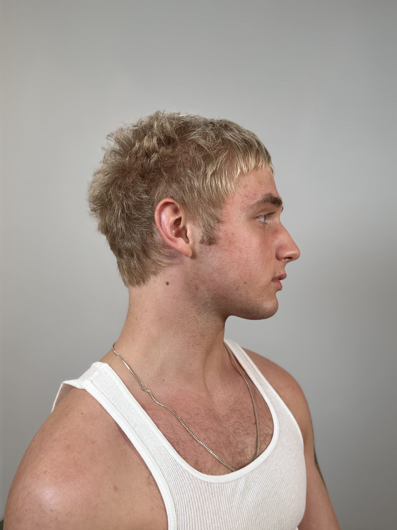 Short textured blond haircut in profile